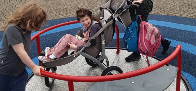 A child enjoys a wheelchair accessible roundabout