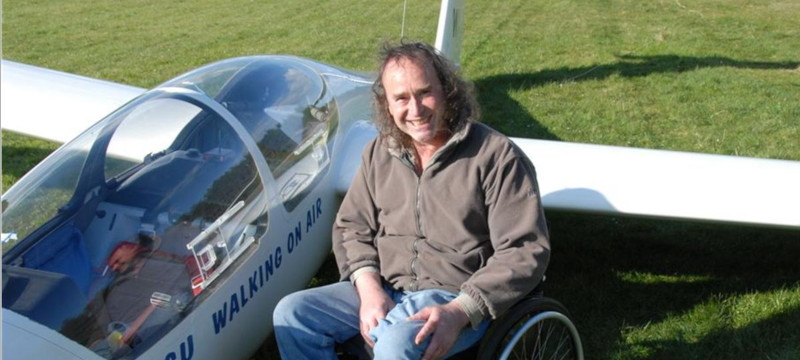 Photo of a glider next to a pilot sitting in a wheelchair.