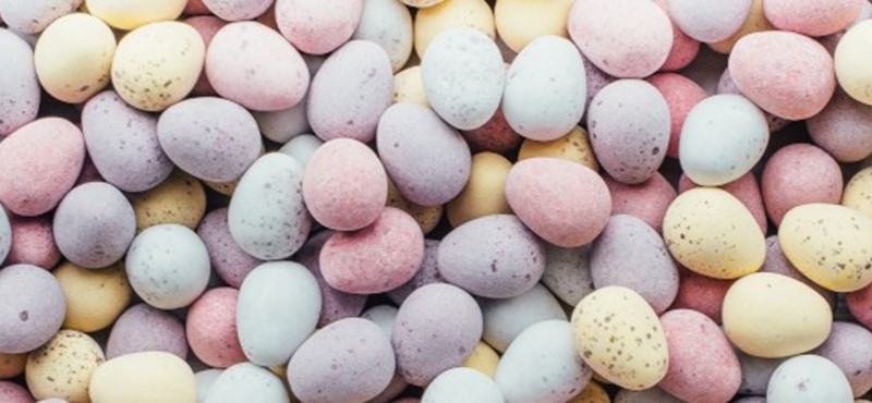 Photo of sugar-coated chocolate eggs on a plain background.