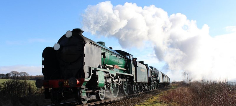 Photo of a steam locomotive traveling through the Hampshire countryside on a sunny day.