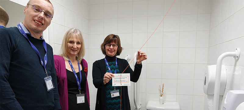 Staff at Disability Action Yorkshire showing their red emergency cord in their accessible toilet