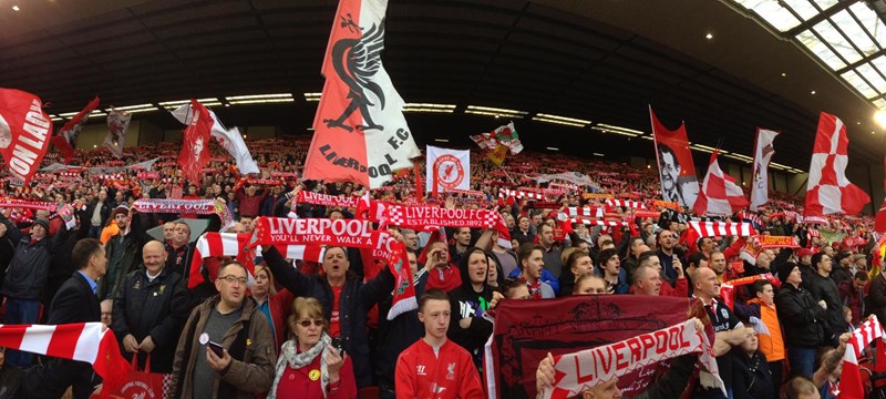 Image of Liverpool Football Club fans holding up scarves.