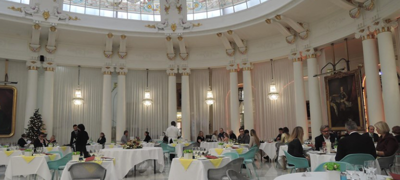 Image of a white fancy dining hall with various chairs and tables arranged in a circle.
