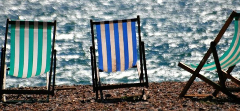 Image of 3 striped deck chairs facing the sea on a stony beach.