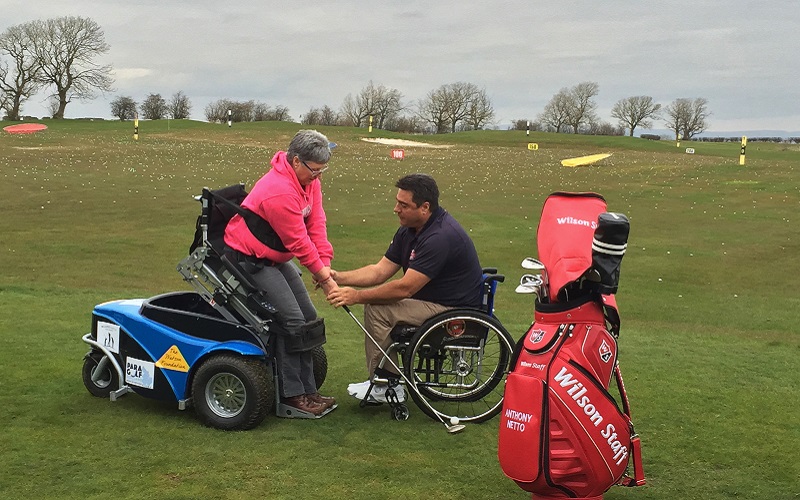 Photo of Anthony Netto and a lady using the paragolf machine.