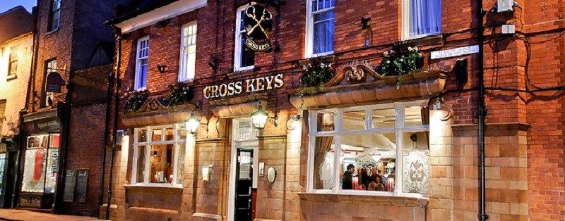 A building with a brick exterior and signage indicating it is The Cross Keys restaurant.