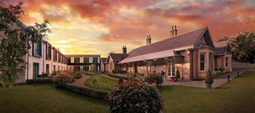 An exterior shot of the Ness Walk Hotel with a cloudy orange sun set 