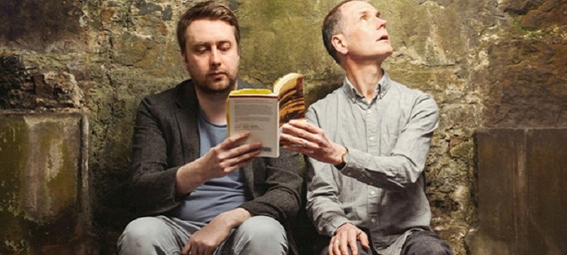 Photo from the production of Our Fathers showing two men holding a book.