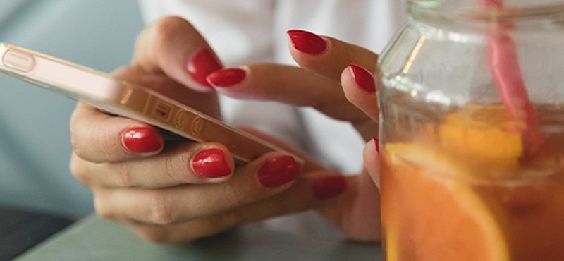 Photo of a drink and a lady holding a phone.