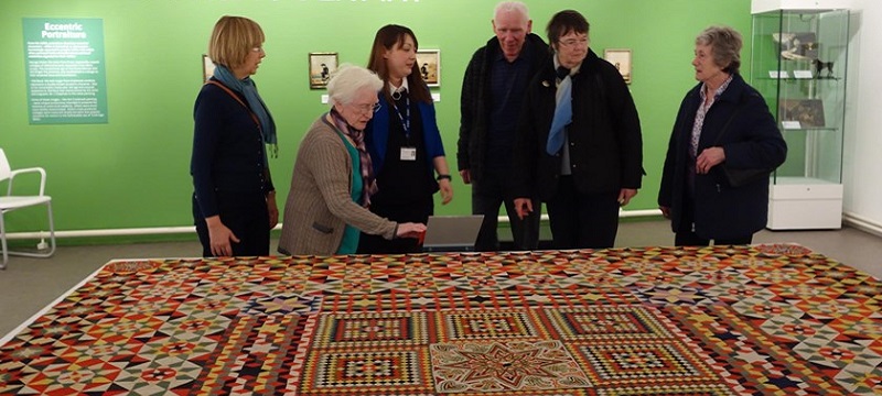 Photo of people looking at a rug in the gallery.