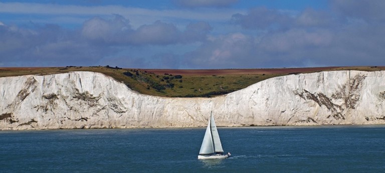 Photo of the white cliffs of Dover and a yacht.