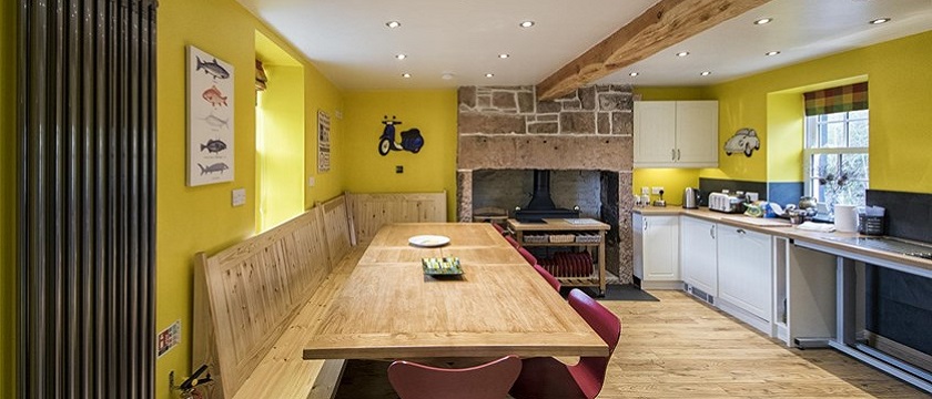 Photo of a yellow kitchen with large wooden table in The Moat House.