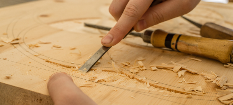 Photo of hands carving a piece of wood.