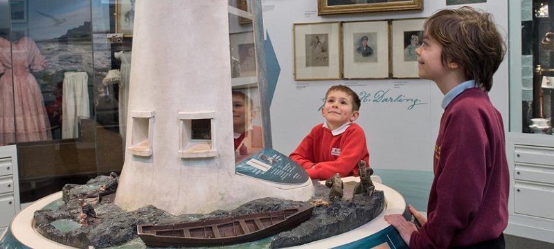 Photo of two children at the RNLI Grace Darling Museum admiring a lighthouse miniature display.