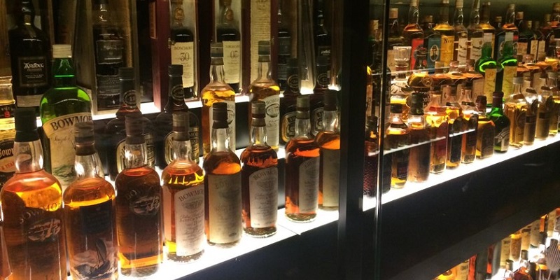 Photo of hundreds of bottles of whisky in shelves.