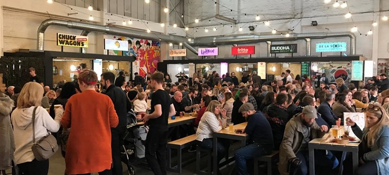 Photo of street food stalls and crowd seating, eating and chatting at Baltic Market.