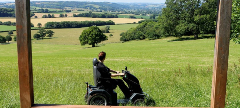 Photo of a visitor using a mobility scooter to cross a grassy field.