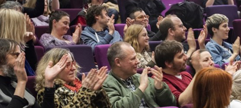 Image of people sitting down and clapping their hands