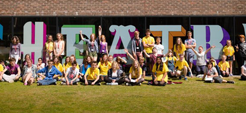 Image of a group of people surrounding letters spelling out theatre