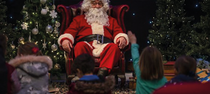 Image of Santa sitting on a chair with children around him