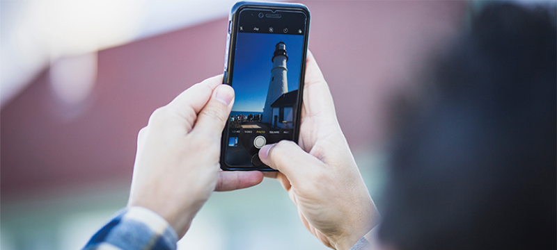 Image of someone taking a picture of a lighthouse