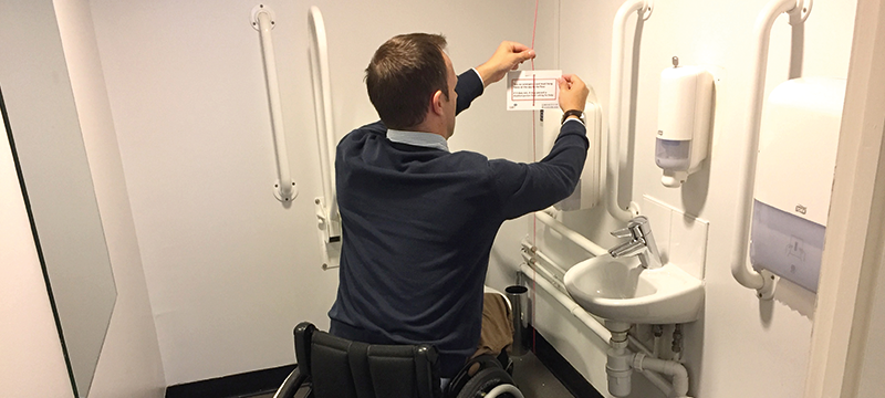 Image of a man hanging a Red Cord Card on a red emergency cord