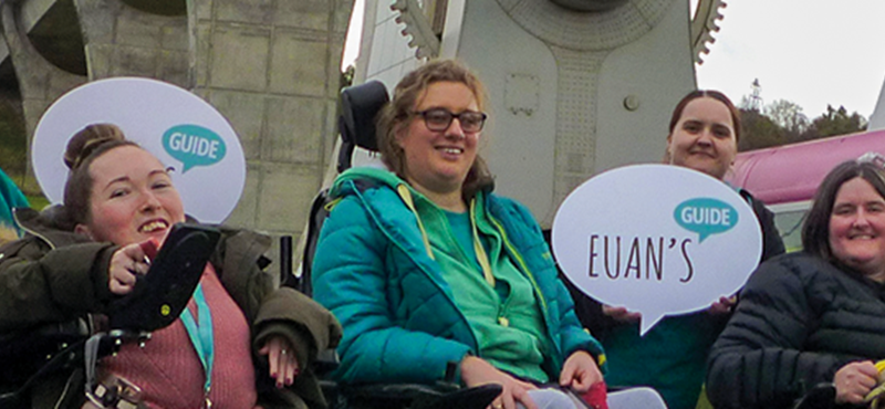 Photo of Euan's Guide Ambassadors infront of the Falkirk Wheel holding up Euan's Guide signs.