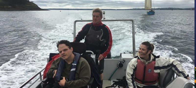 Image of three people including on wheelchair user on a sailboat