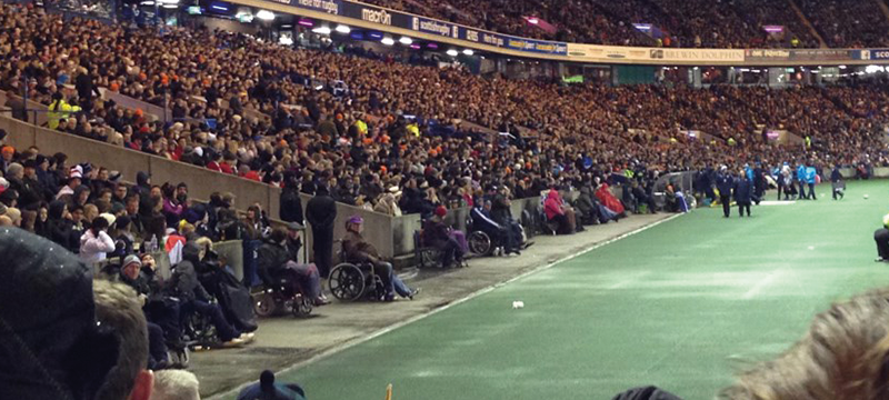 View of side of pitch at Murrayfield Stadium. A number of wheelchair users are watching the game.