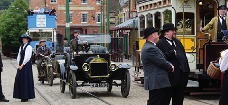 Image of character performers in an old looking town with tram cars and carts.