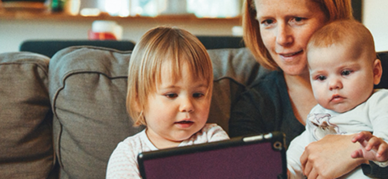 Image of a mum on a couch with her children looking at an iPad