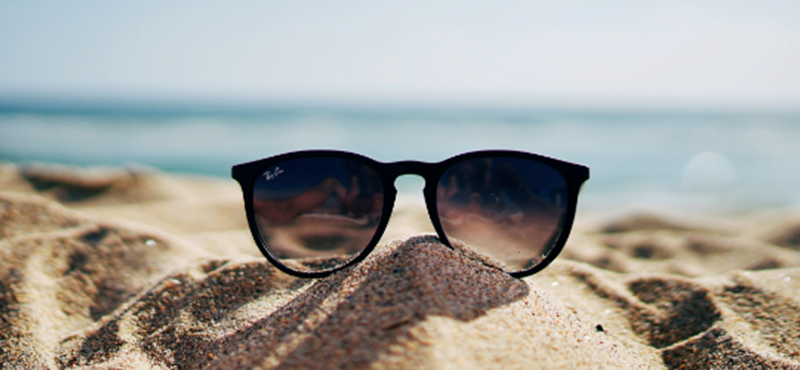 An image of sunglasses lying on a beach