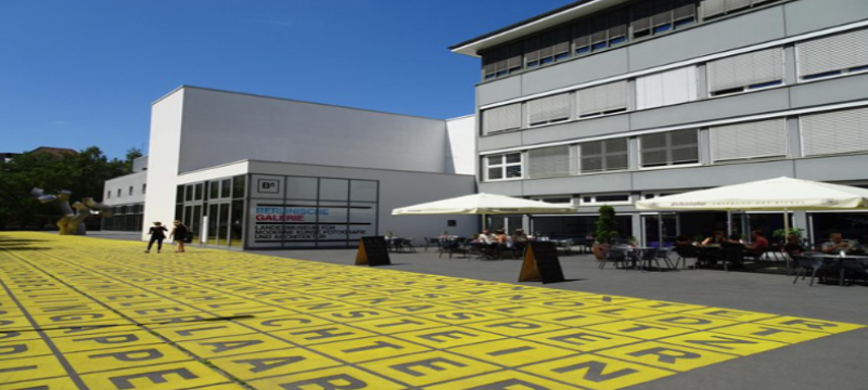 Image of a museum with tables and chairs off to the right of the entrance,