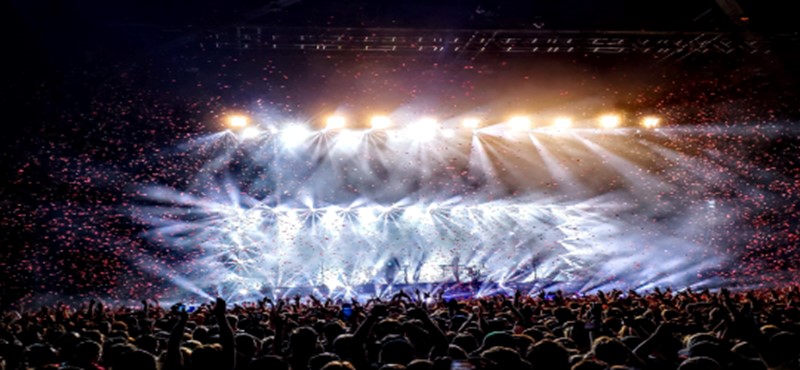 An image of a concert with peoples hands in the air. 