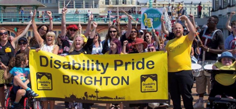 Image of people gathered in Brighton holding a Disability Pride Brighton banner