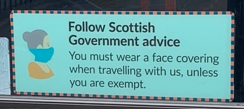 A sign on a bus window that reads “Following Scottish Government advice. You must wear a face covering when travelling with us, unless you are exempt.”