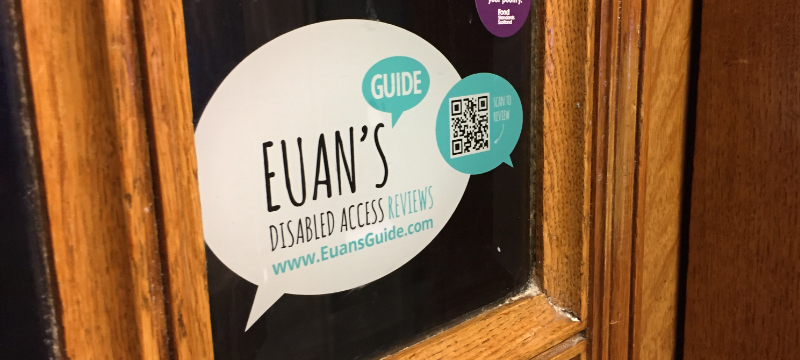 A window with a wooden frame. A sticker placed on the window has the Euan's Guide logo with a QR code and text that says "scan to review".