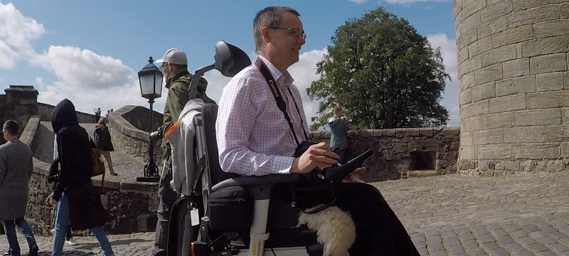 A side of picture of Paul travelling on a cobbled road.