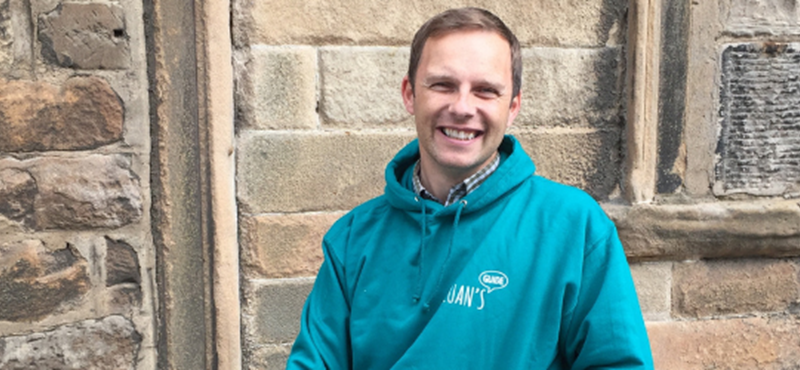 Image of Ryan in a Euan's Guide hoodie against a stone wall.