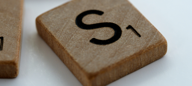 Wooden square title with the letter 'S' on it from a game of Scrabble.