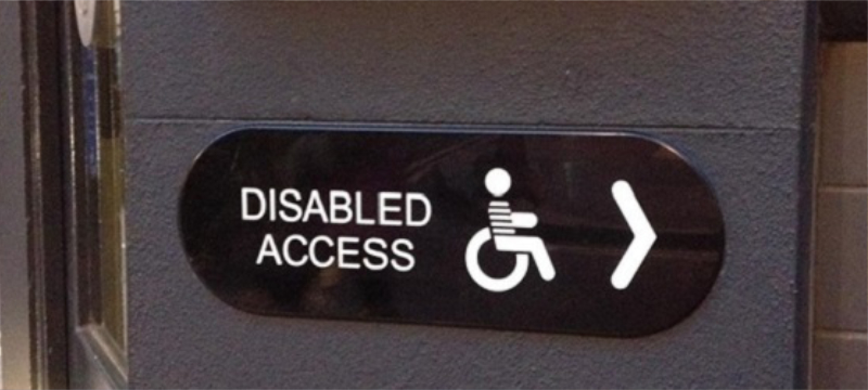 A sign with "disabled access" written on it. There is an icon of a wheelchair user and an arrow pointing to the right.
