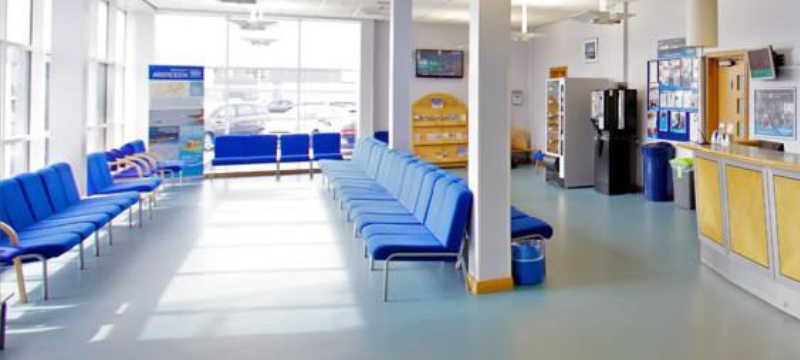 Rows of blue chairs at a waiting area. Some have arm rests and some don't.