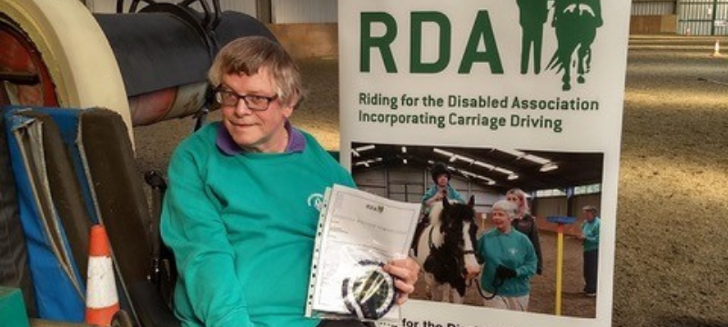 Image of Neil sitting in front a poster that reads RDA.