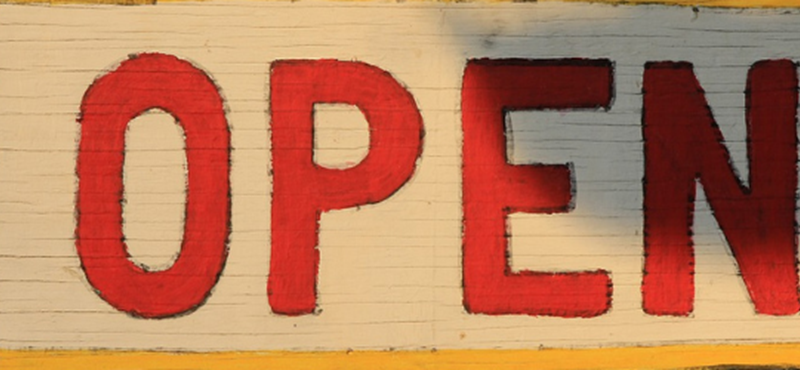 Image of a sign with the word open written on it in red letters