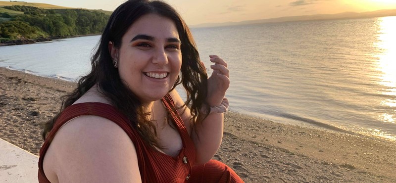 Photo of Iman Mackenzie on a beach with the sun setting behind her.