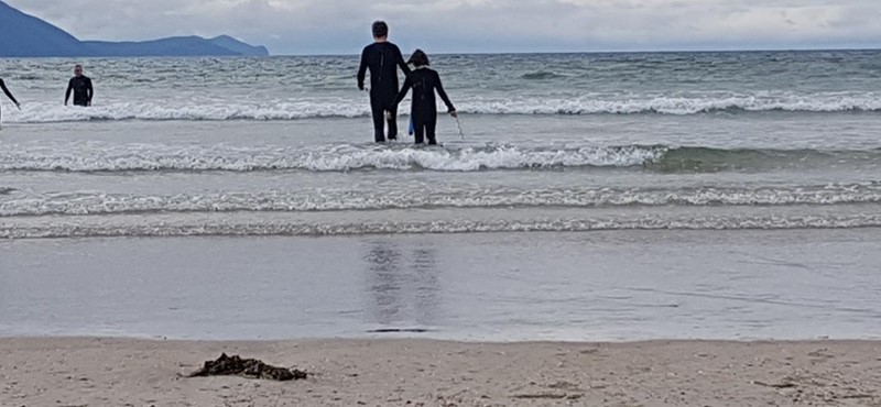 A photograph of a father and son running into the water at Inch Beach.
