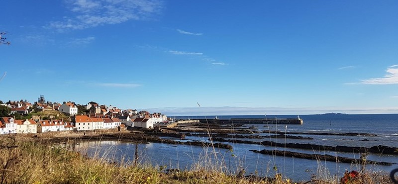 A view of Anstruther from the Fife Coastal Path of cottages and apartments on the left and the water on the right.