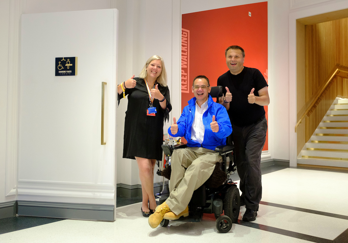 Three people with their thumbs up outside the Changing Places Toilet at Johnnie Walker Princes Street.