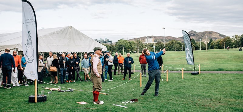 A group of golfers and event attendees mingling at a marquee on green grass