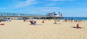 A sandy beach at Bournemouth with a pier and people sunbathing